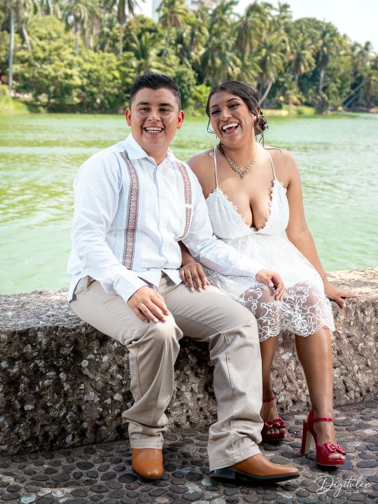 Retrato de pareja sentada junto al agua.